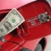 Red car with dollar bill going into gas tank, to illustrate story on saving money on gas