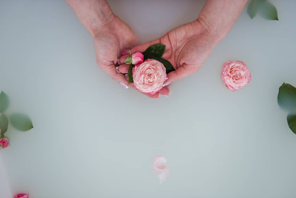 Closeup of woman's hands holding pink flowers in water