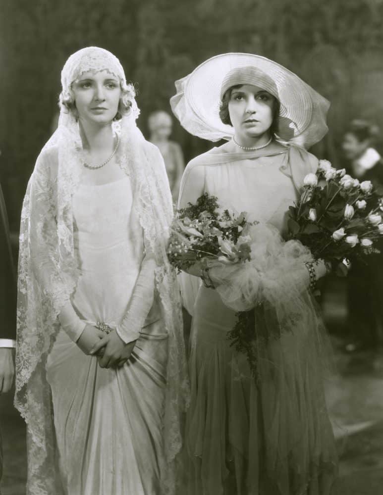 A black-and-white photo of two women in vintage wedding attire.