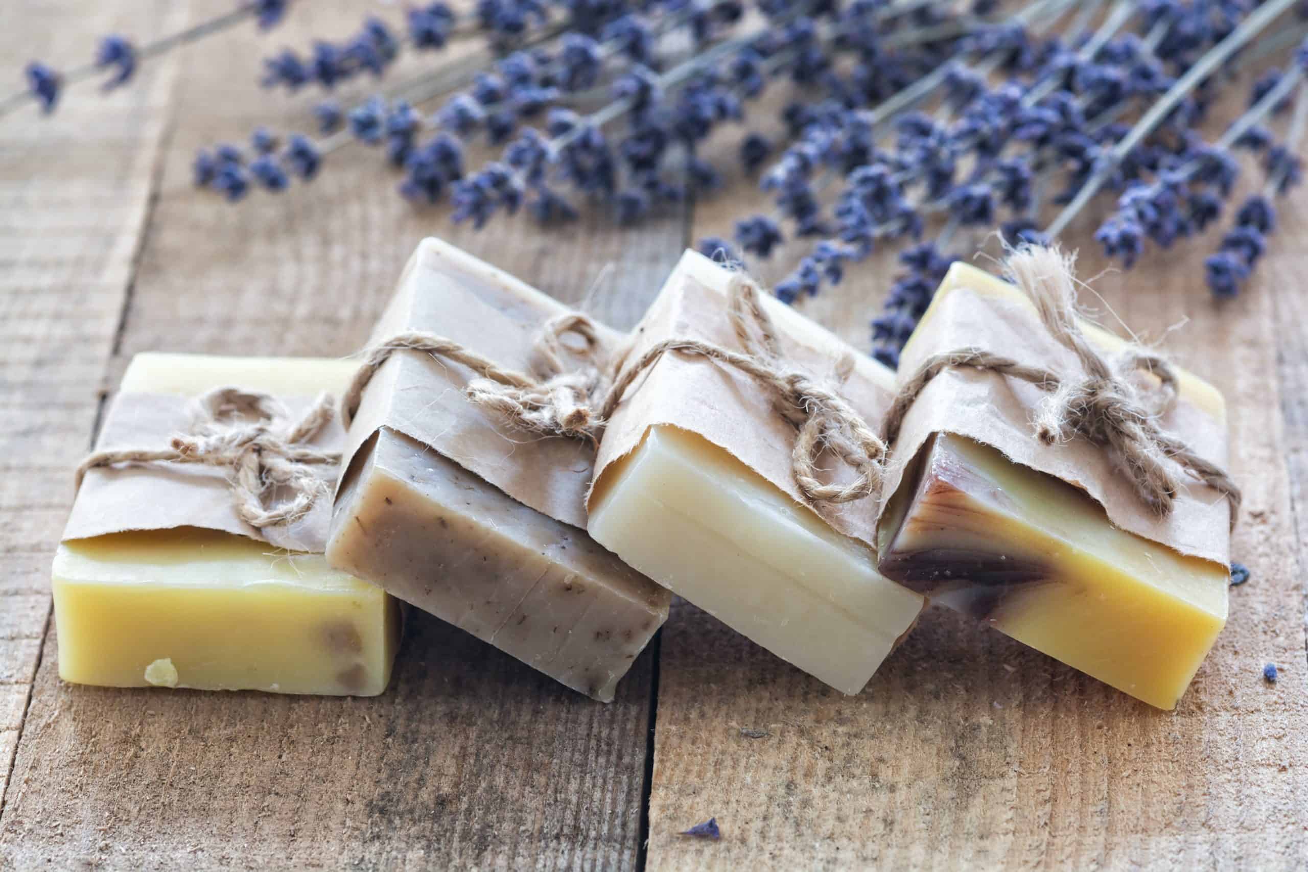 Save on skin care - Bars of soap leaning against each other on a wood table with lavender in the background