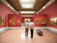 Two men looking at paintings in a museum