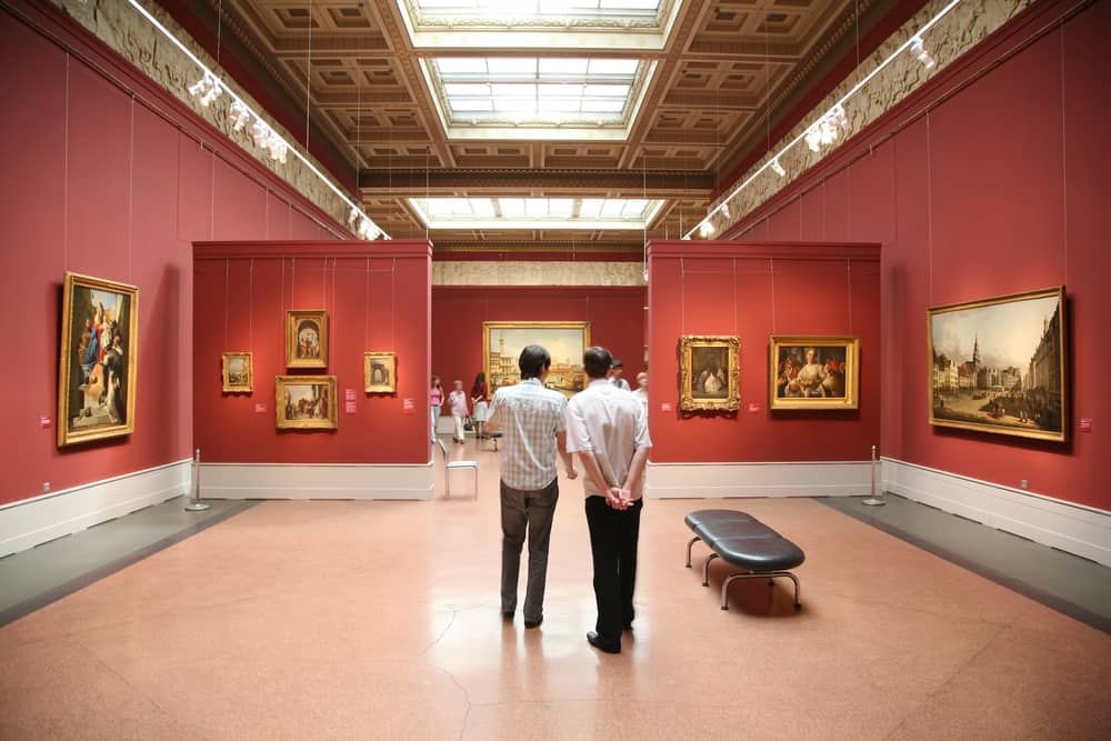 Two men looking at paintings in a museum