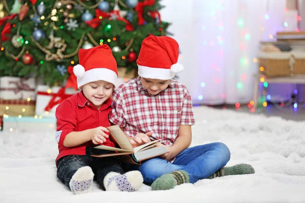 Dois rapazes lendo livro sobre fundo de decoração de Natal