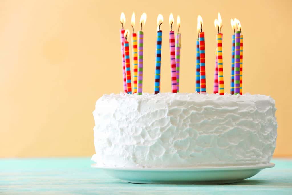 A white birthday cake with colorful candles