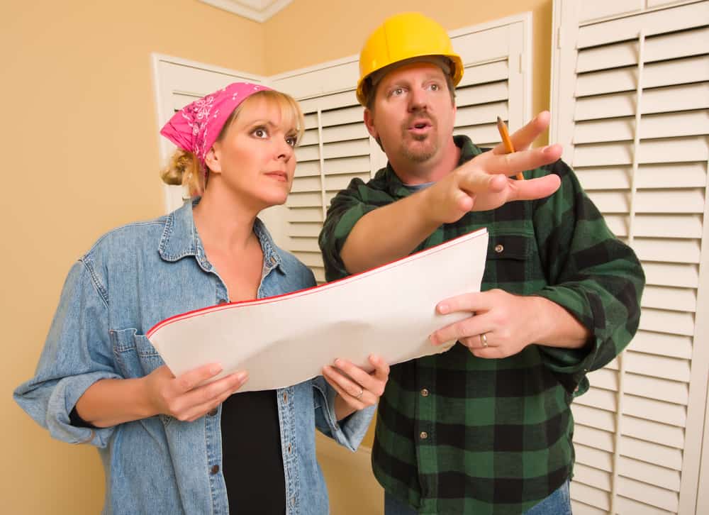 A woman speaking to a contractor with blueprints in her hand.