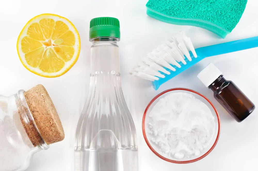 A bottle of vinegar, baking soda, a cut lemon and a toothbrush and sponge make for cheap cleaning supplies.