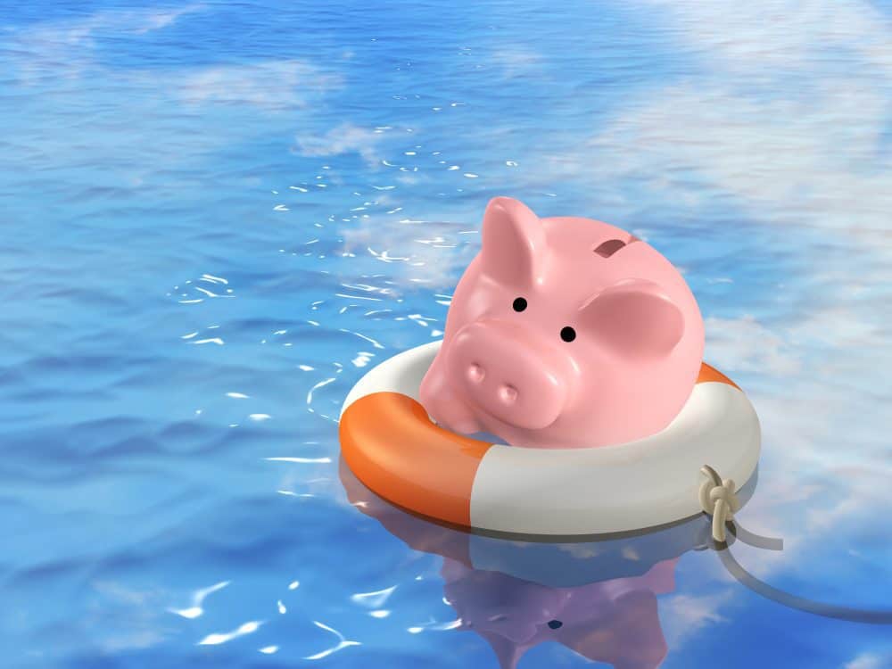 Piggy bank in a life preserver on blue water.