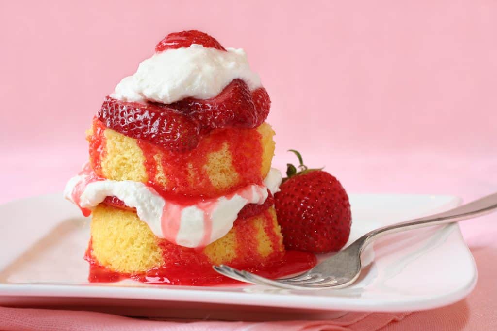 Strawberry shortcake on a white plate on a pink backdrop