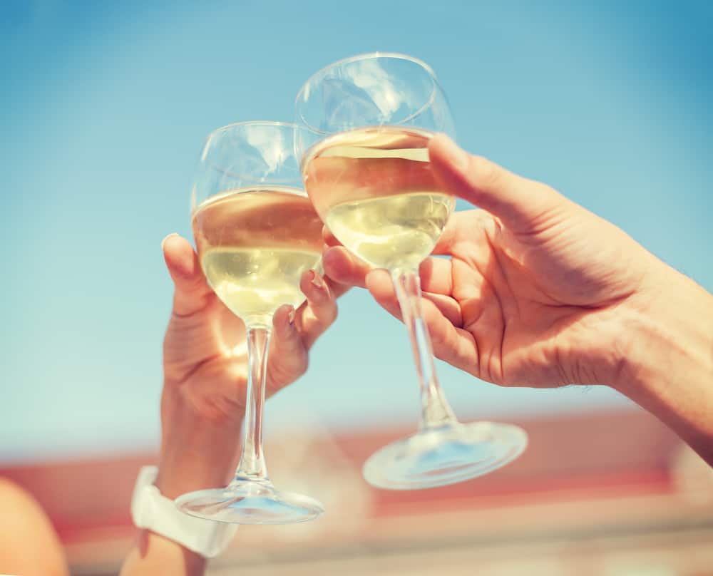 Closeup of two hands holding glasses of white wine