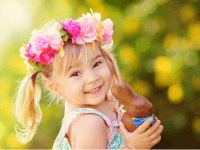 little girl with pink flowers in hair holding chocolate bunny
