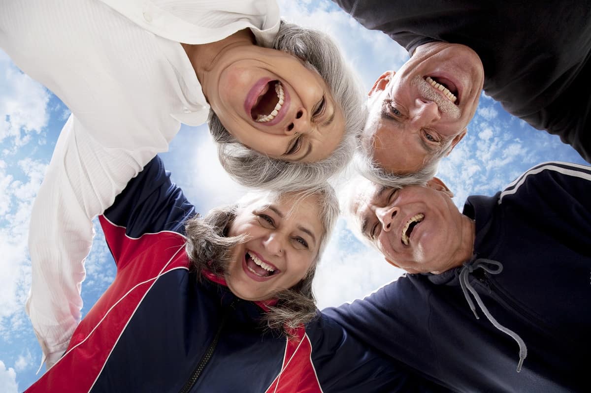Two men and two women, all with gray hair, laughing and being photographed from below