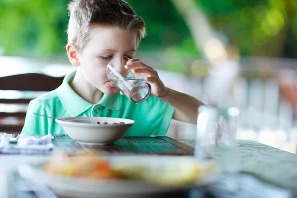 A child drinking a glass of water.