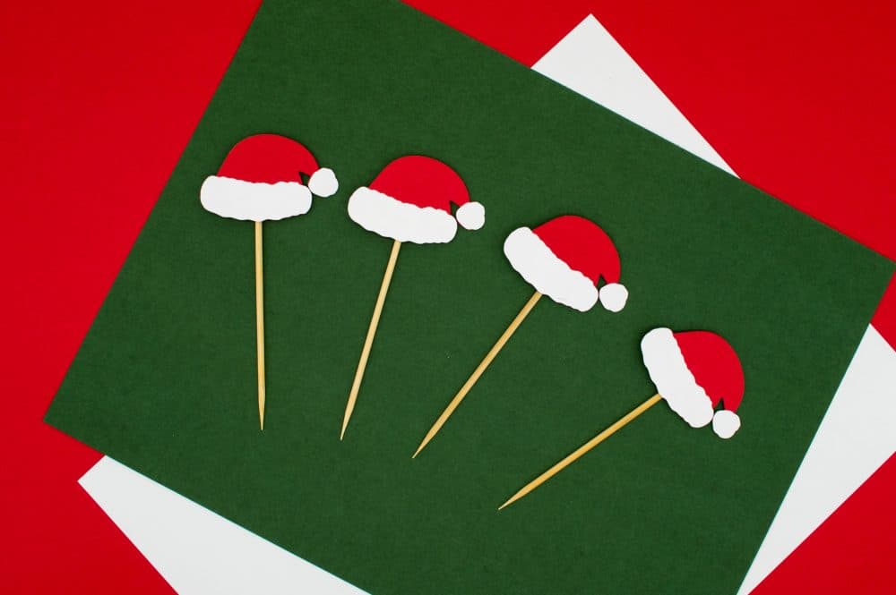 Santa hats on a green card with white envelope in background.