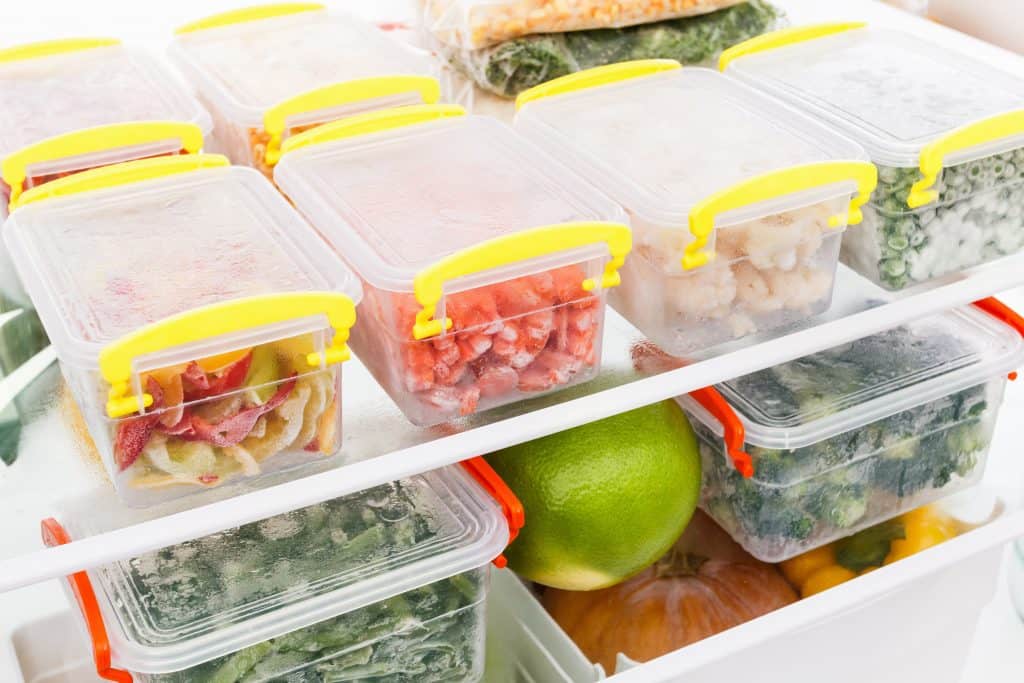 Plastic containers in a refrigerator filled with food.