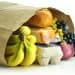 Bananas, bread and other groceries in a paper bag.