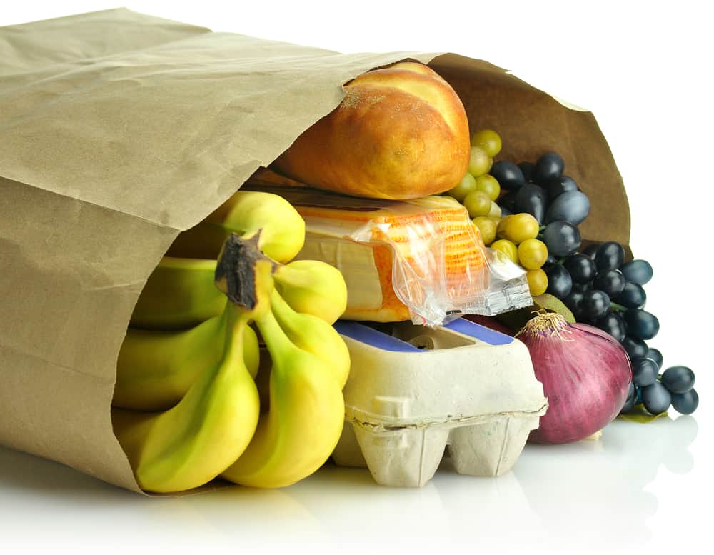 Bananas, bread and other groceries in a paper bag.
