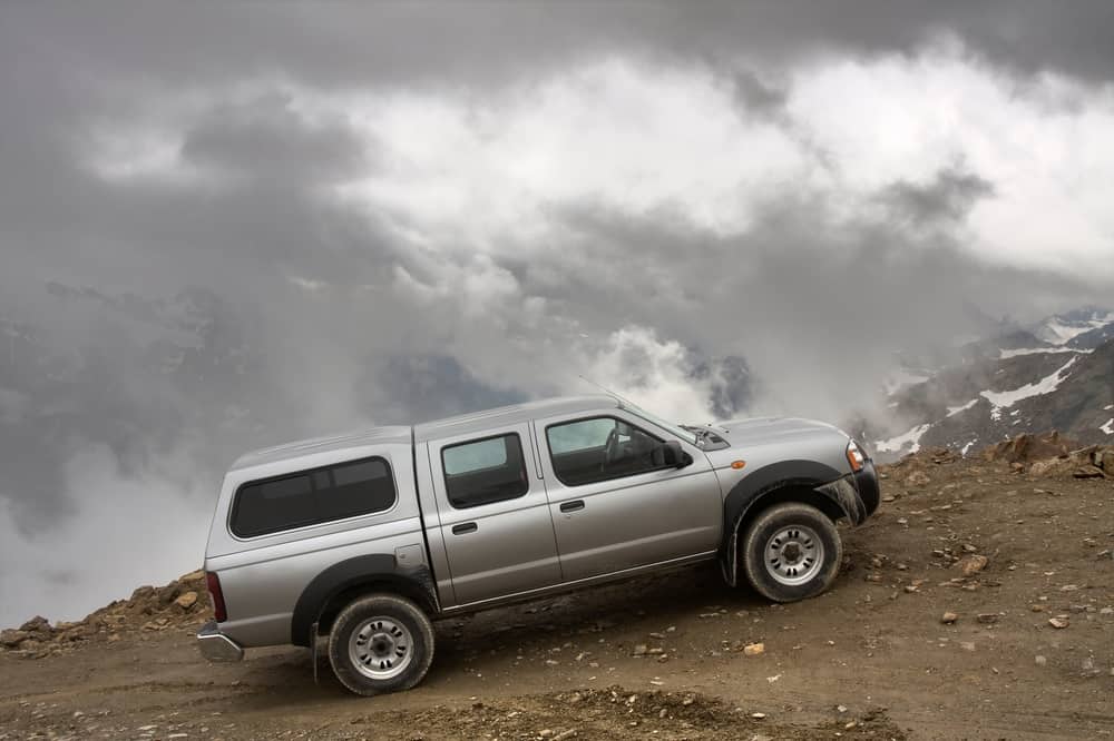 Truck heading up a steep incline with cloudy sky in background