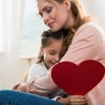 Mother and daughter embrace with homemade heart card