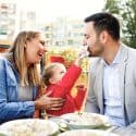 Mom, dad and young daughter eating pasta in restaurant.