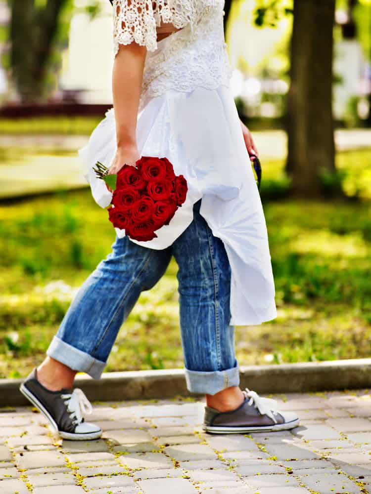 A bride wearing a wedding dress over jeans and sneakers.