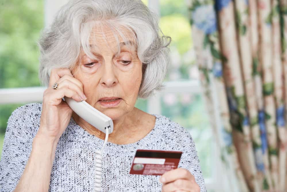 Older woman on phone holding a credit card