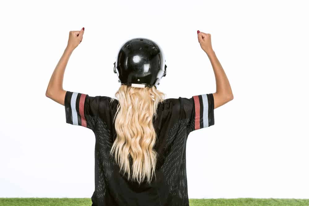 blonde woman in football helmet and jersey cheering