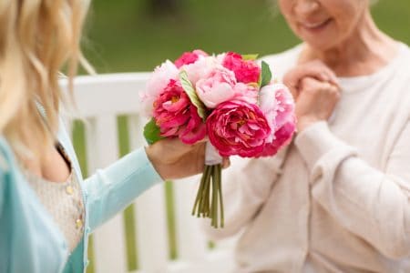 Woman giving flowers to another older woman