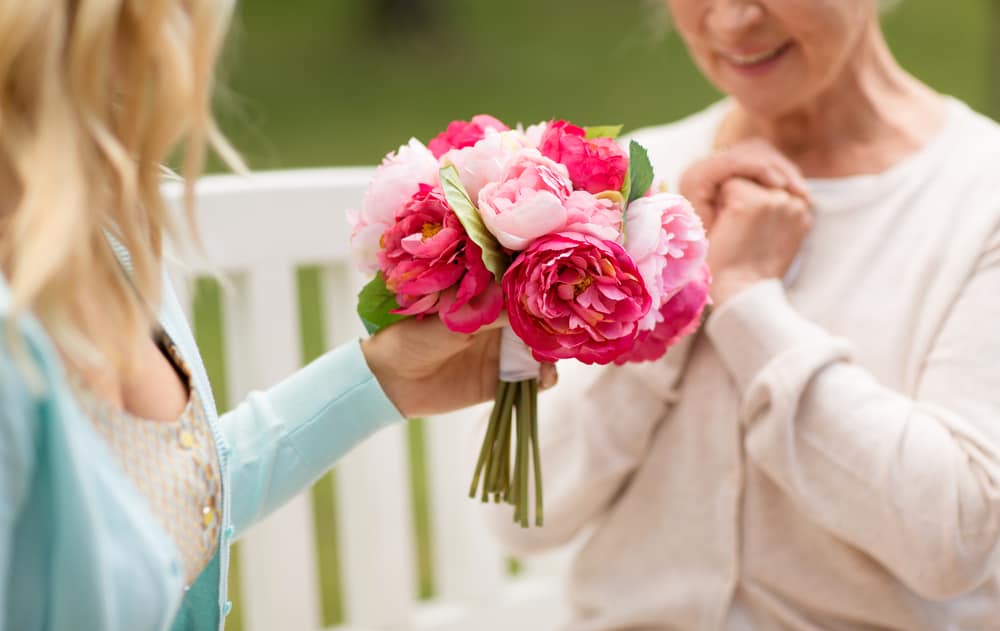 Woman giving flowers to another older woman