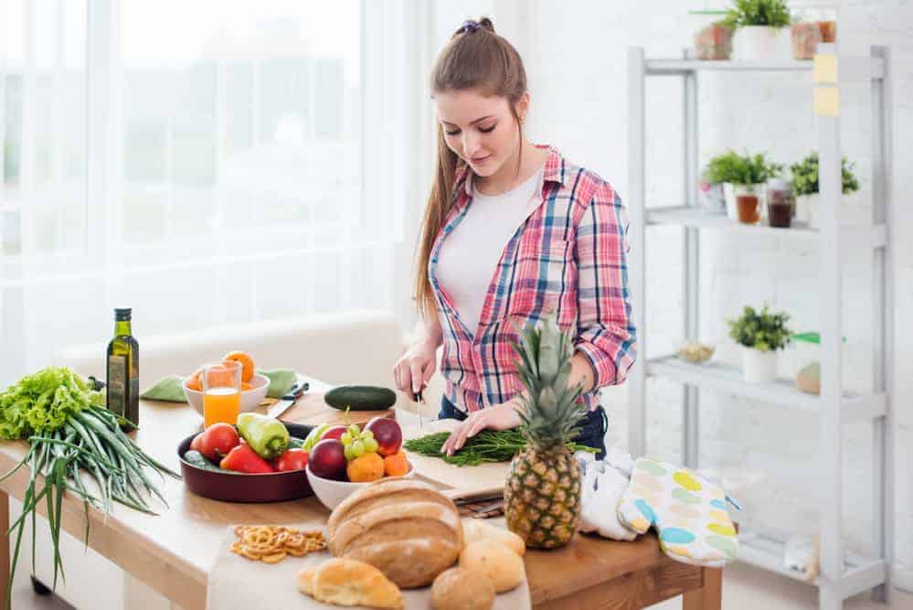 Young woman cutting vegetables on cutting board in kitchen