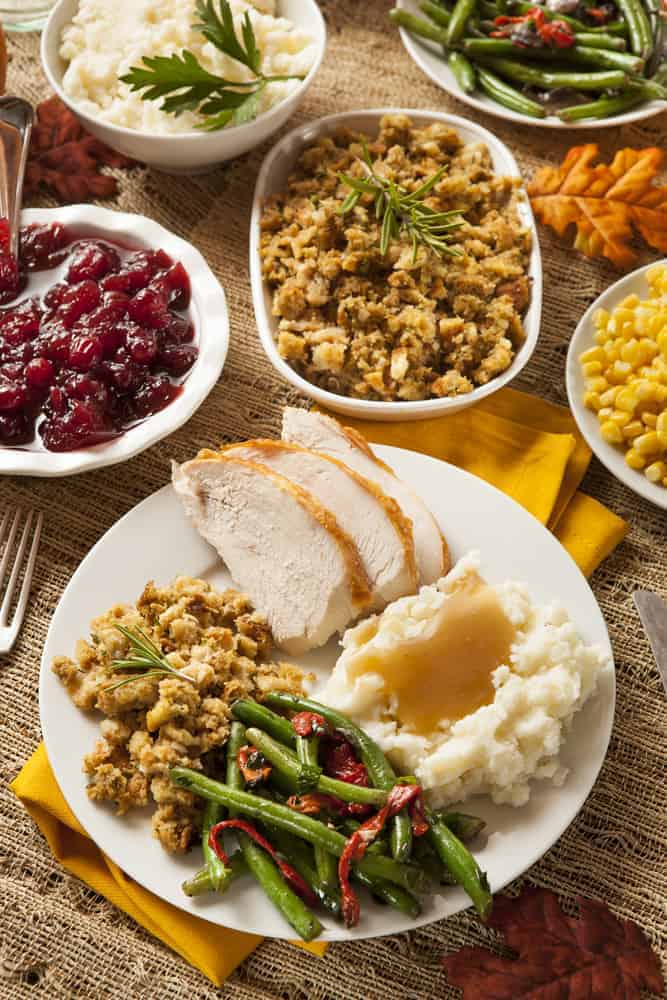 Thanksgiving dinner with all the traditional sides - turkey, mashed potatoes, gravy, green beans, stuffing, cranberries