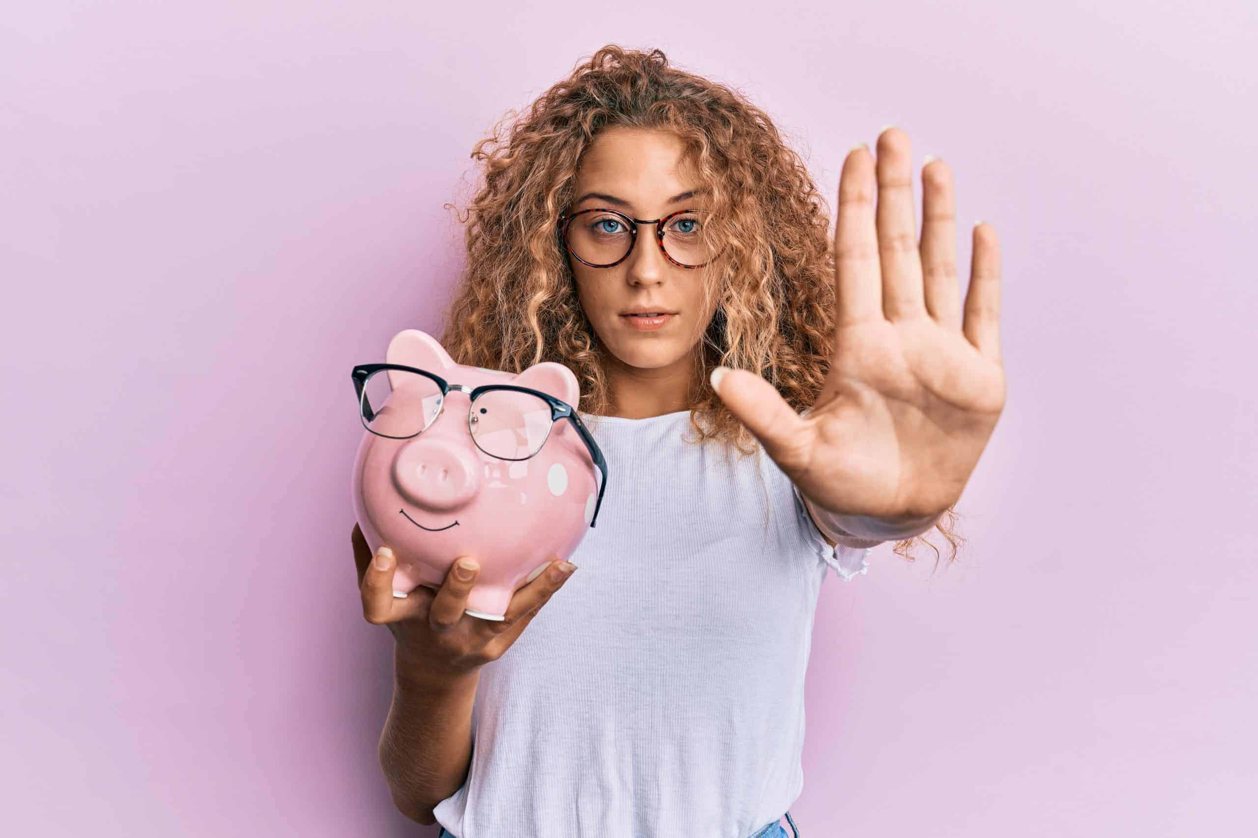 No spend month challenge - Woman holding piggy bank signaling stop