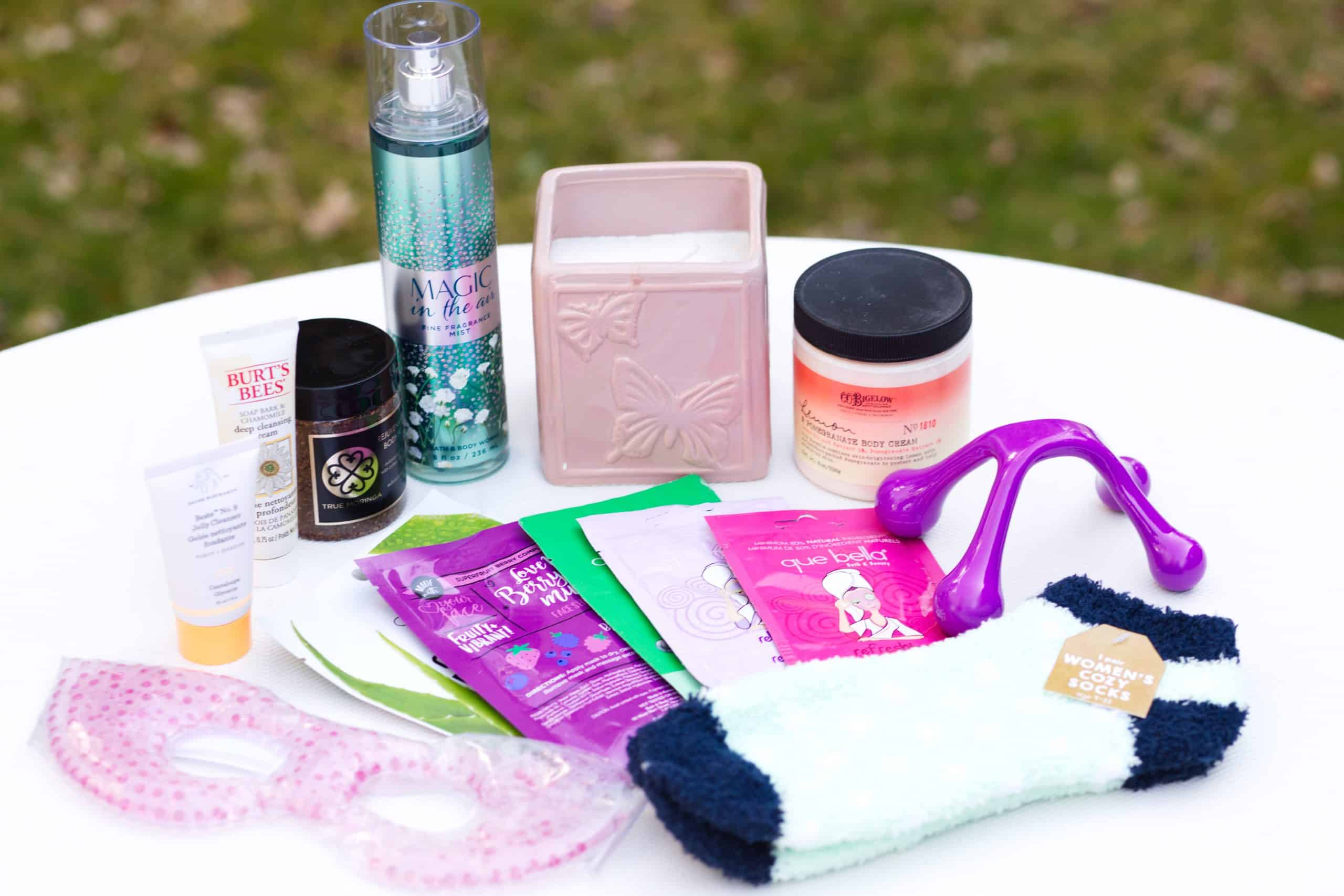 Homemade spa day gift basket - Several spa gifts arranged on table - eye mask, socks, body scrub, candle, face mask