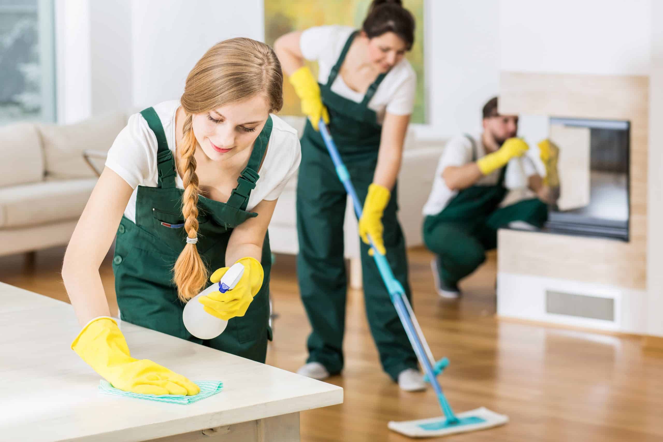 Spend time to save money - Team of 3 house cleaners in green overalls clean a living room
