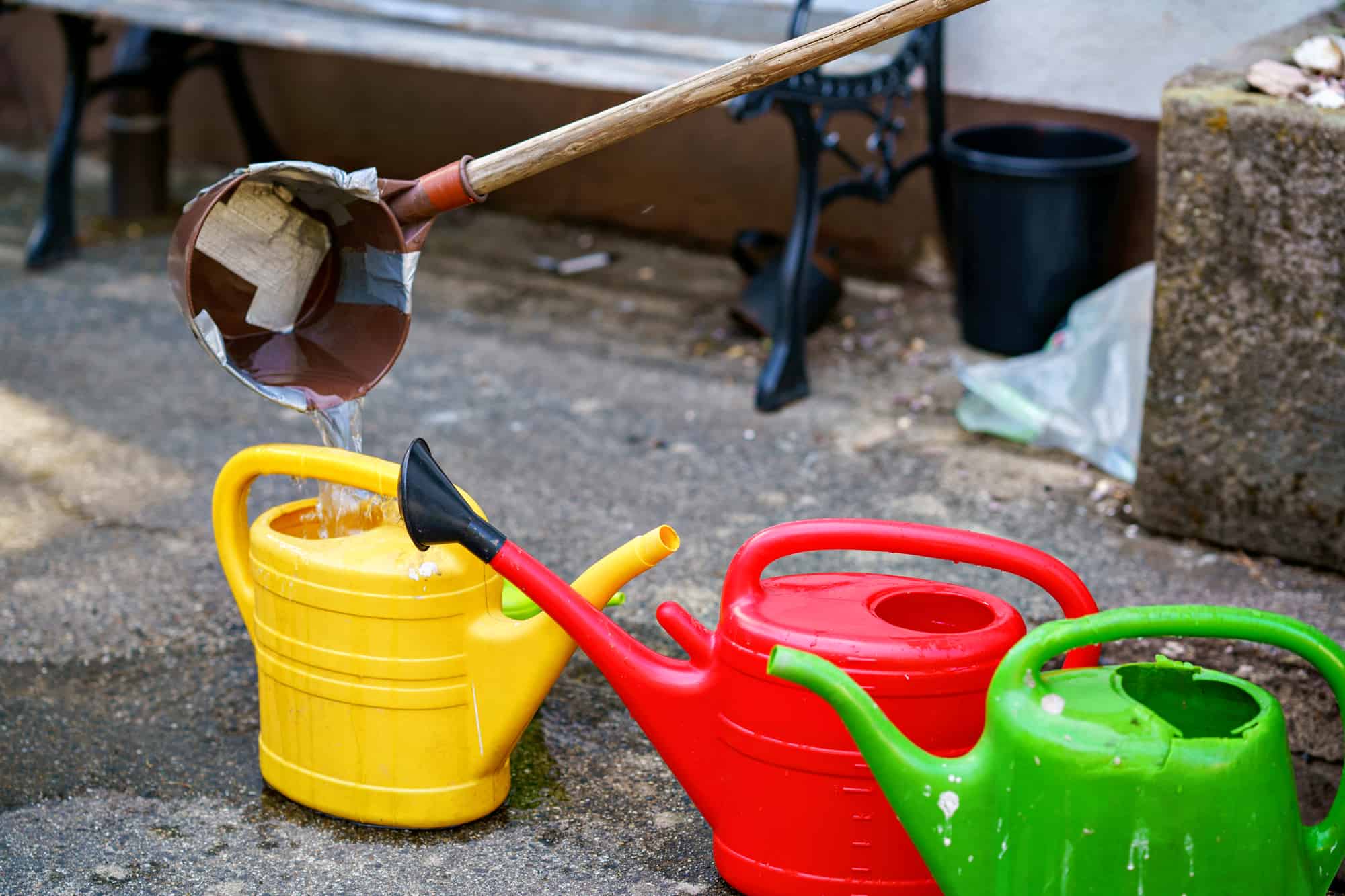 A yellow, red and green watering can receiving recycled rainwater 