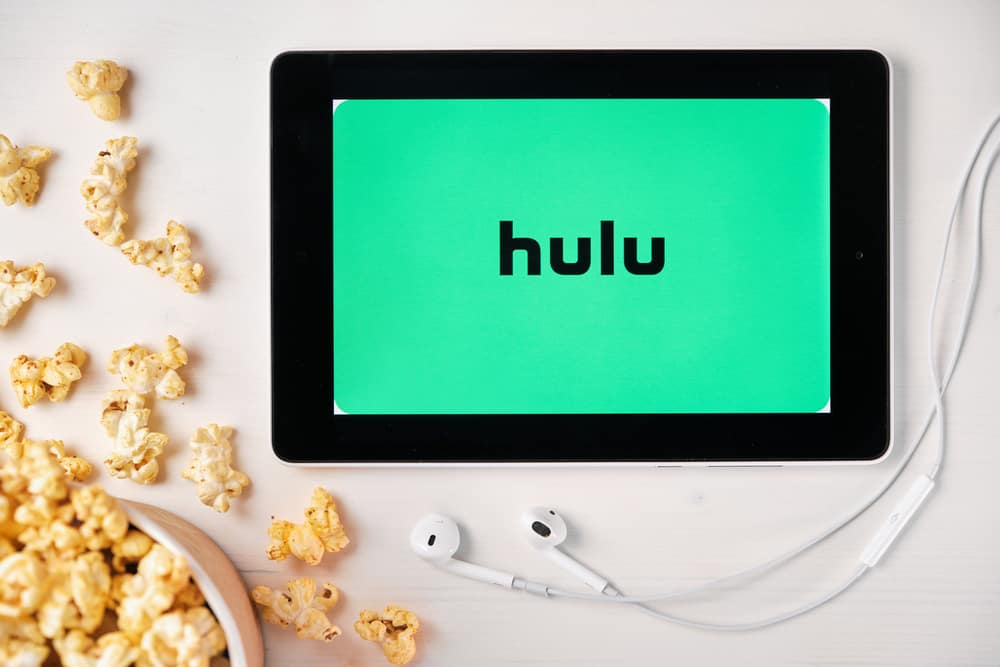 Tablet with hulu logo, surrounded by popcorn and earbuds.