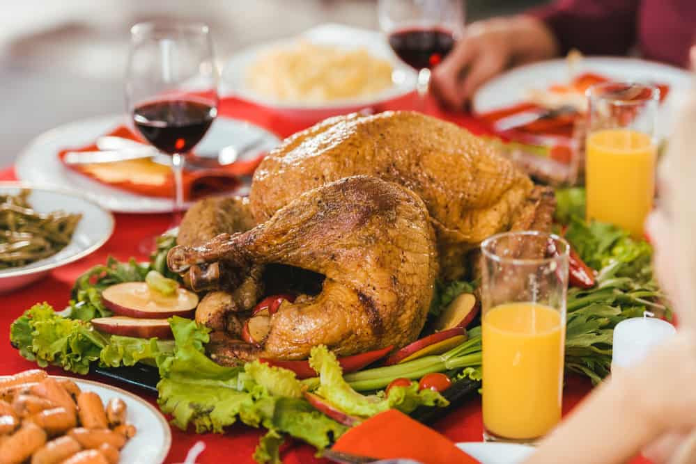 A Thanksgiving turkey on a table surrounded by traditional side dishes.