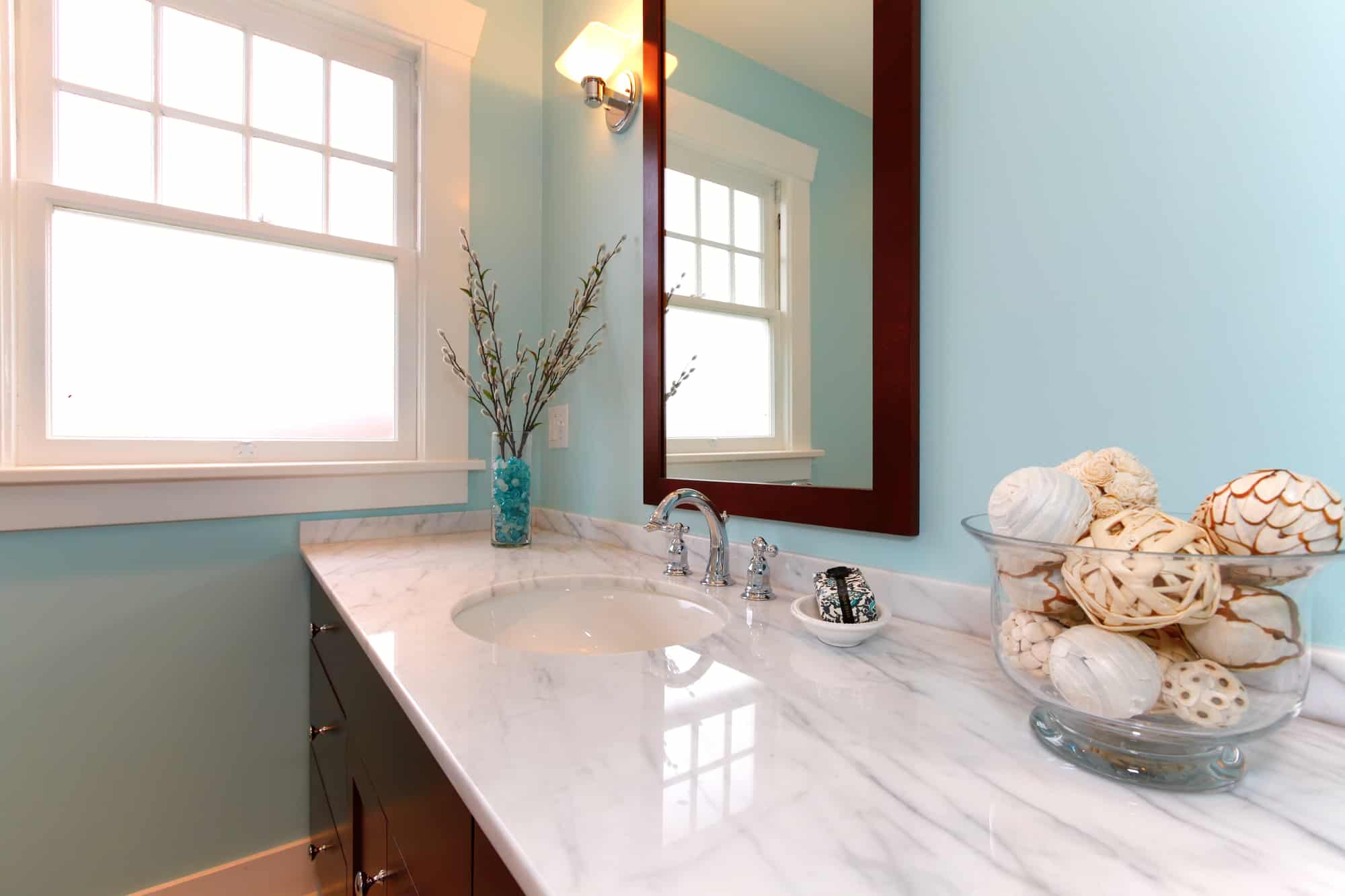 Bathroom with white granite sink, blue walls and wood-framed mirror