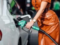 Closeup of woman's torso as she fills car with gas.