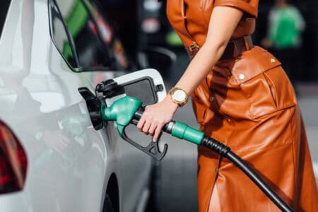 Closeup of woman's torso as she fills car with gas.