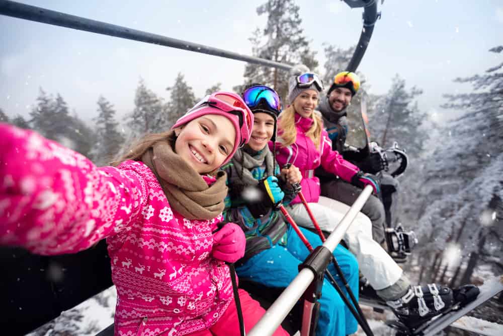 A family of two adults and two children on a ski lift.