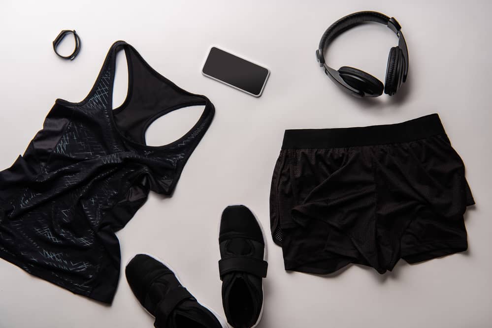 Black workout top, shorts, headphones, shoes, smartphone and smart watch.