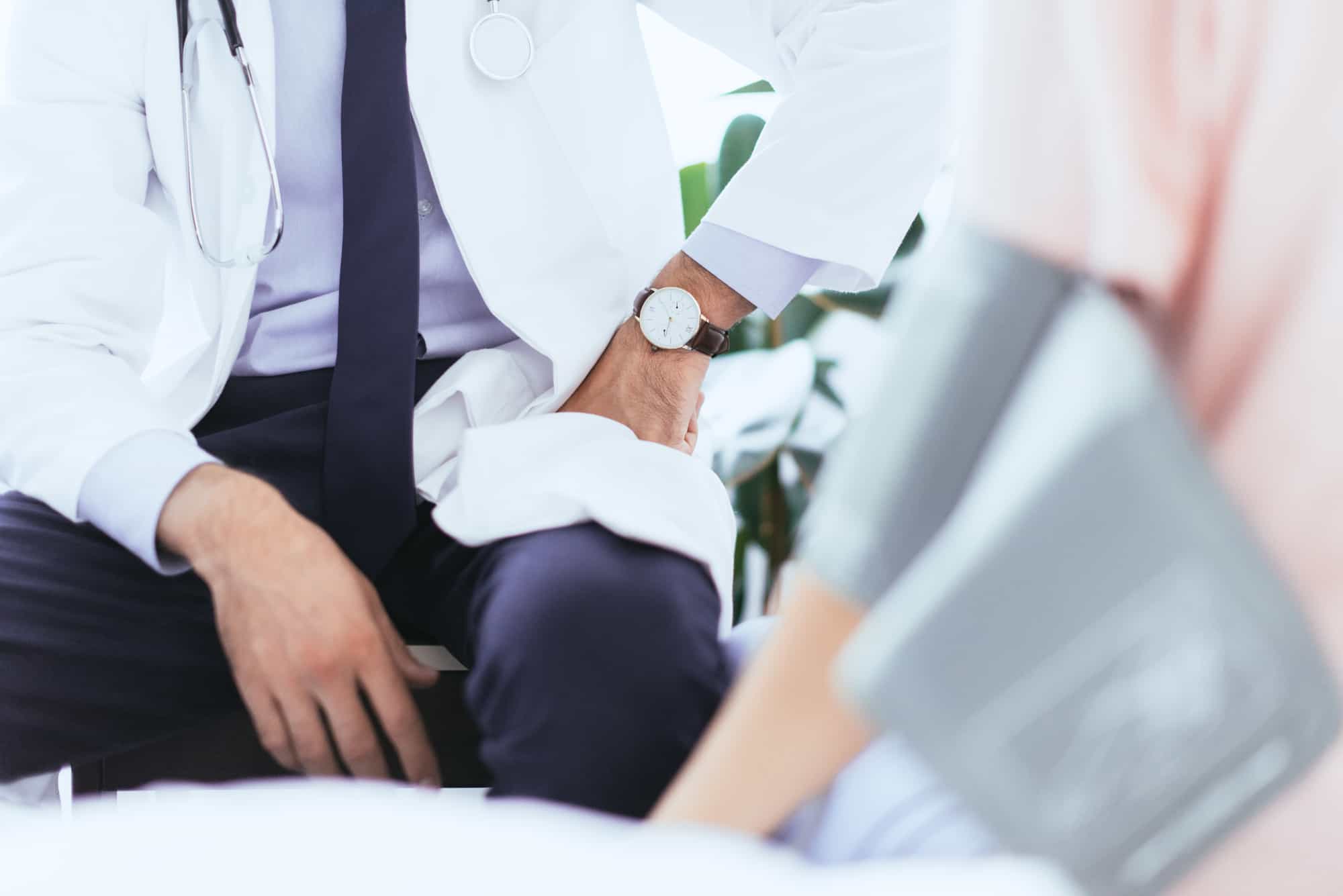 Closeup of doctor in white coat speaking with patient.