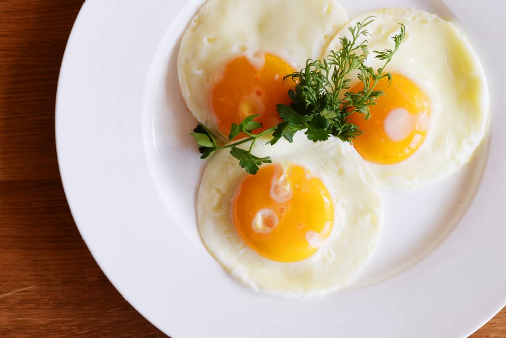Fried eggs on a plate sprinkled with herbs.