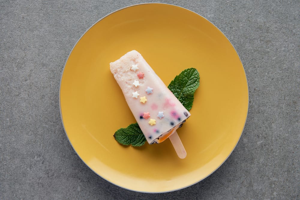 DIY popsicle with frozen sprinkles on a plate.