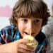 Boy eating cupcake with candle at birthday party;