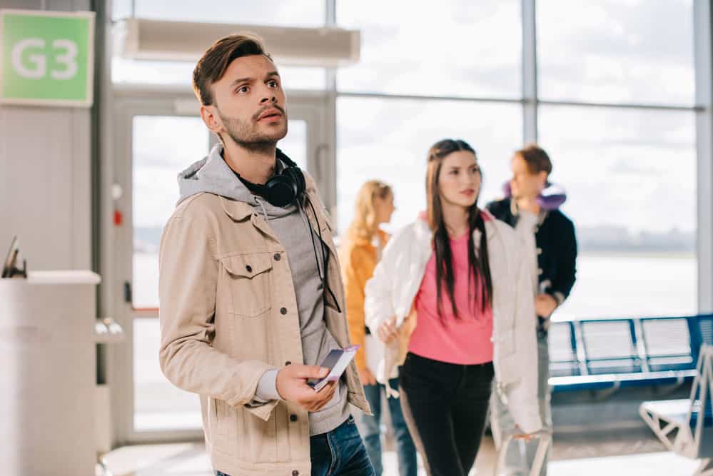 Young man in airport looking worriedly at something in the distance