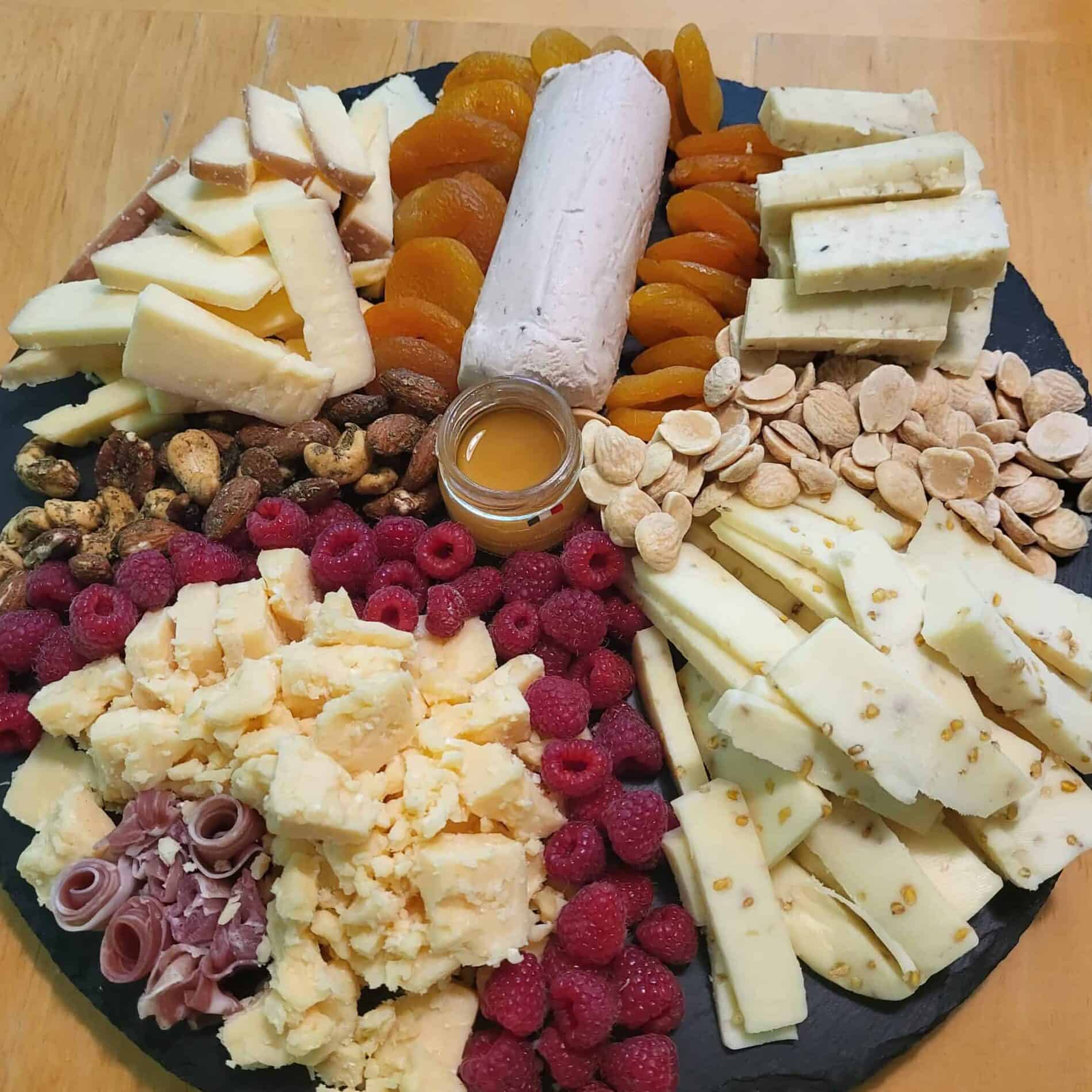 A charcuterie board with almonds, cheeses and raspberries