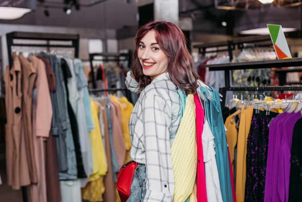 Smiling woman amid clothing racks in thrift store.