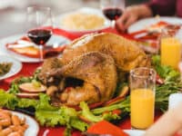 A Thanksgiving turkey on a dining table surrounded by side dishes.